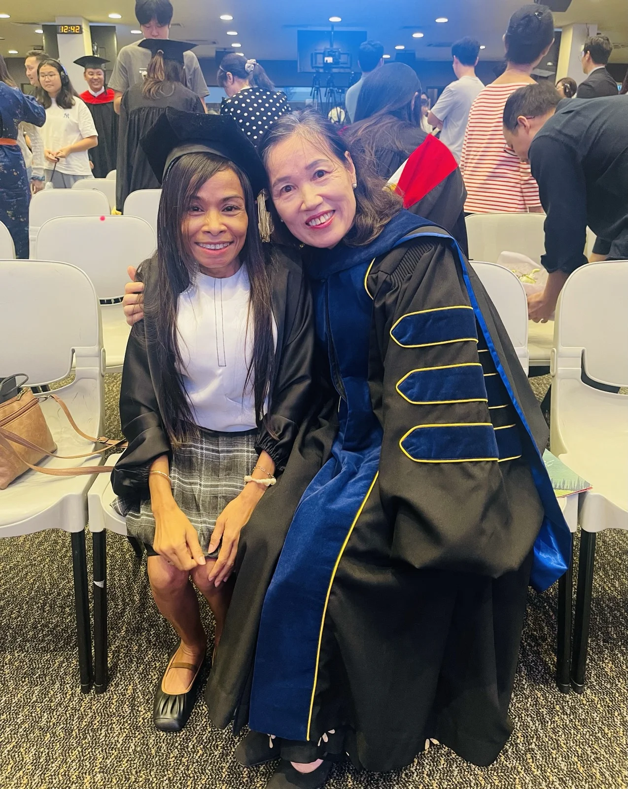Naleng Real in a graduation cap and gown with a faculty member in academic robes at the 2026 EEC graduation