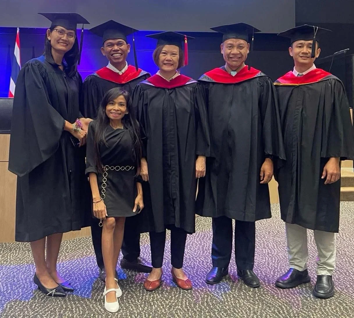 Naleng Real with five graduates in caps and gowns after an EEC graduation ceremony