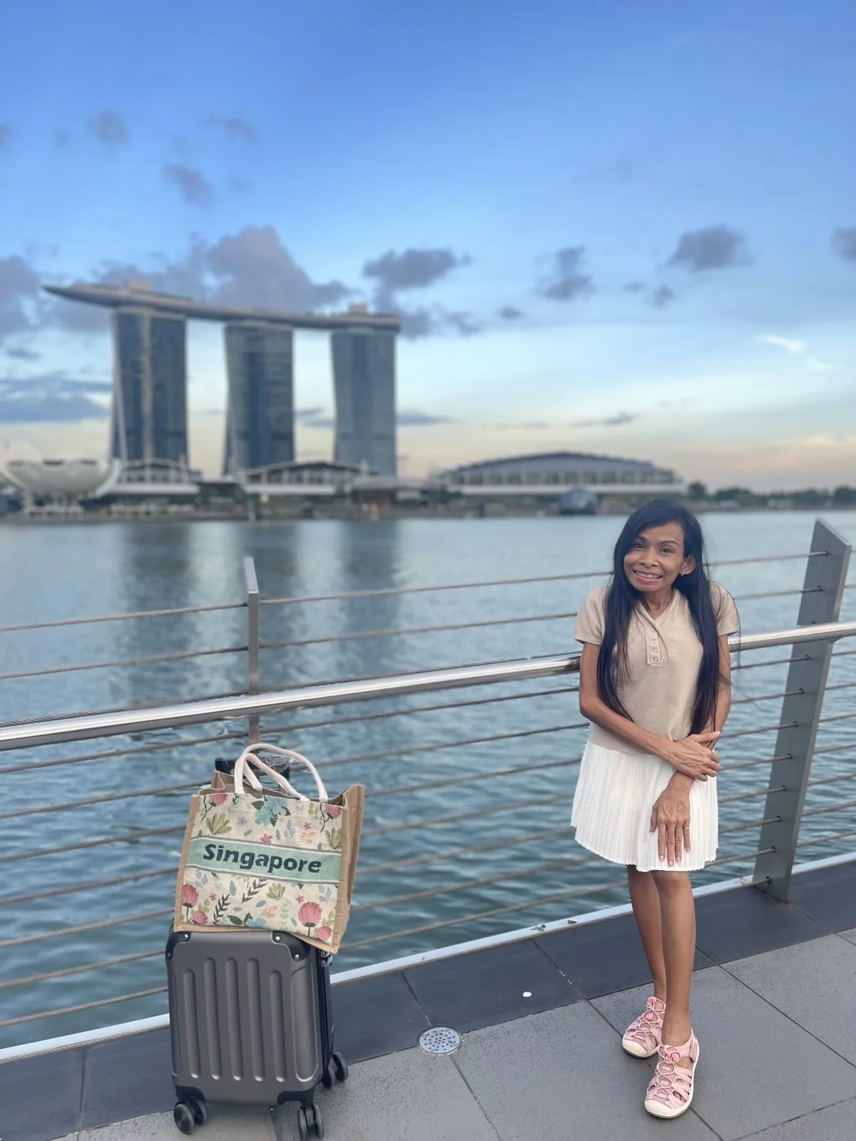 Naleng Real beside the water at Marina Bay in Singapore with her luggage