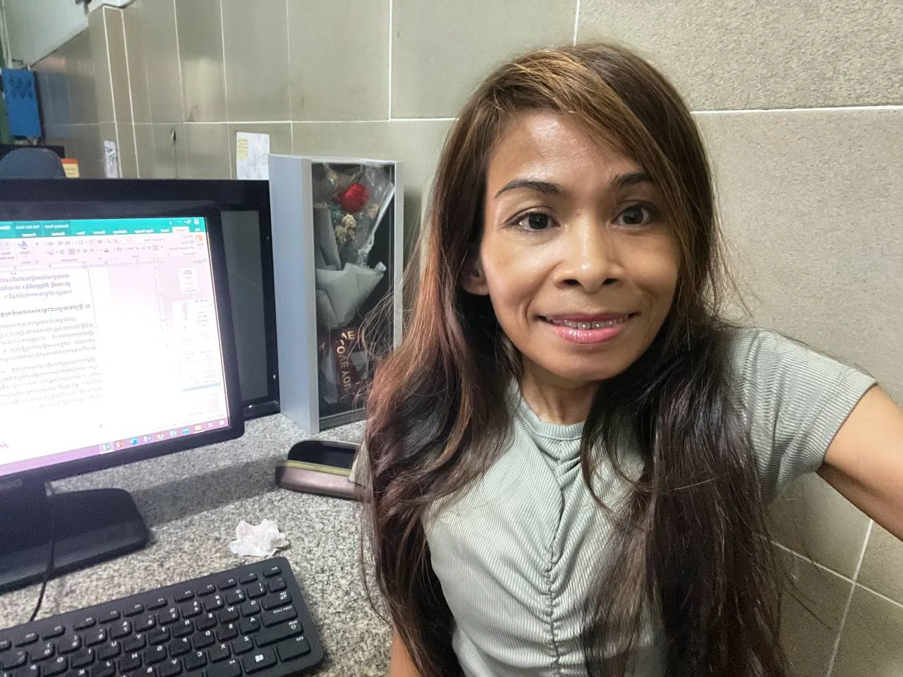 Naleng Real at her office computer with a Khmer document open on screen